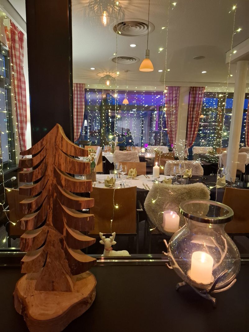 View through the window into the dining room laid for Christmas, with a wooden tree and a lantern in front